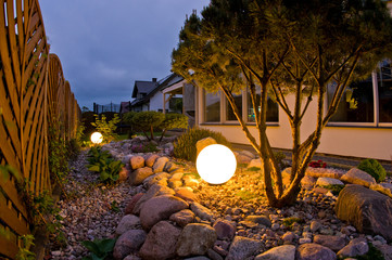Home garden at night, illuminated by globe shaped lights.