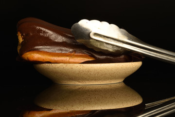 Sweet, mouth-watering chocolate eclairs, close-up, on a black background.