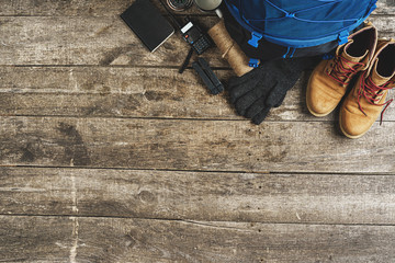 Backpack and hiking equipment on wooden background, top view
