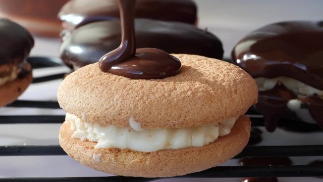 Dripping chocolate ganache over sandwich cookies on wire rack