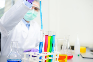Young doctor scientist in the laboratory making experience research about covid19 coronavirus vaccine wearing white lab coat a mobcap and surgical mask