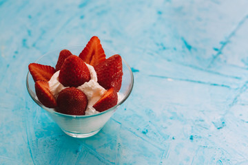 Strawberry glass bowl with whipped cream on a blue background