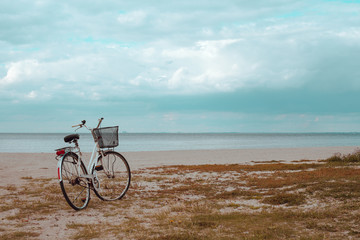 Fototapeta premium Bikes at the Beach of the Sea. Vintage Beach Cruiser Bike. Bicycle parked on beach. Retro bike near the sea. Bike on the background of the sea horizon.
