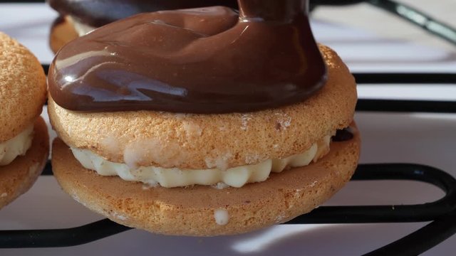 Pouring chocolate ganache over sandwich cookies on wire rack