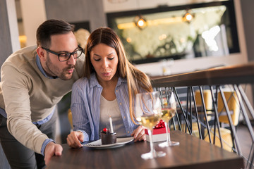 Couple blowing candles on birthday cake