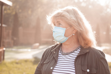 Senior woman in protective face mask respirator, outbreak of viral disease coronavirus covid-2019