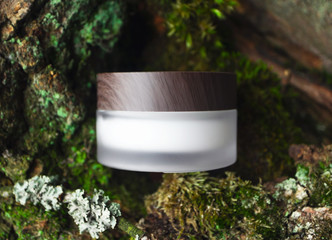 Natural cosmetic face or eye cream skincare blank jar packaging with wooden cup on forest background. Concept eco bio organic beauty product, top view. Tree bark and mosses on backdrop