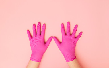 Female hands in protective gloves on a pink background.