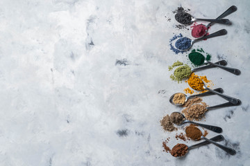 Super powders in spoons - matcha, turmeric, ginger, cocoa, spirulina, chia, cinnamon black sesame top view