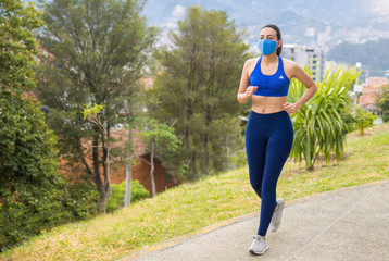 mujer corriendo al aire libre después de la cuarentena con mascarilla o tapabocas por prevención...