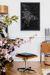 Stylish composition at living room interior with black piano, design stool, black mock up poster map, spring flowers, lamp, furniture and elegant presonal accessories in modern home decor.