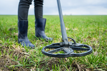 girl archaeologist or metal digger is looking for coins or metal with a metal detector. Search for...