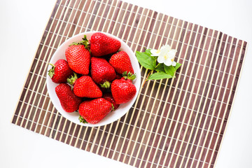 ripe strawberries on a white plate and jasmine flowers