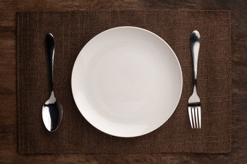 empty plate spoon fork and knife on table. Table setting on wooden table.setting with plate, fork, and spoon on wooden background