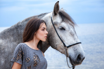 Obraz premium Beautyful woman walking on sea with horse