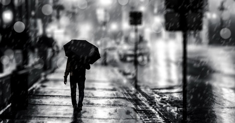 A man with an umbrella on the city street b&w.