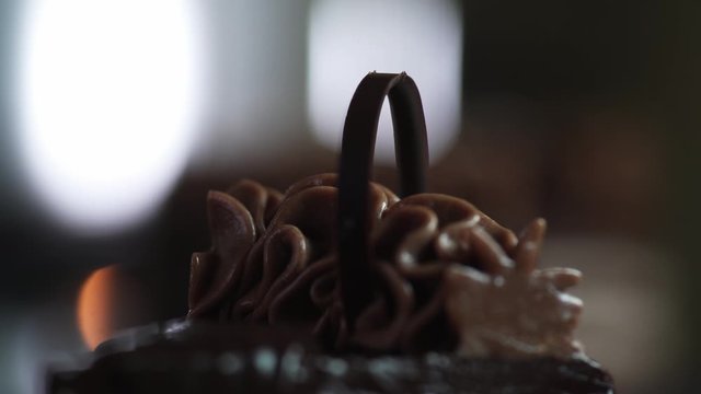 The chef completes the decoration and inserts a piece of dark chocolate with tweezers into the cut slice of the cake