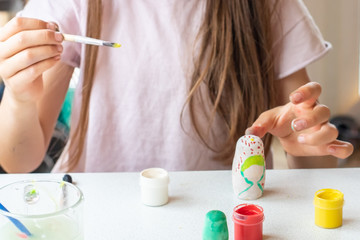 Obraz na płótnie Canvas A child paints a wooden blank of a nesting doll. Children's crafts