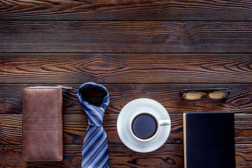 Text near male tie, glasses, coffee on dark wooden background top view copy space