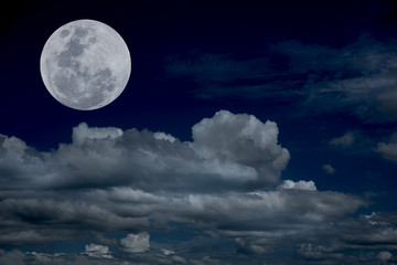 Naklejka na ściany i meble Full moon over clouds on the sky.