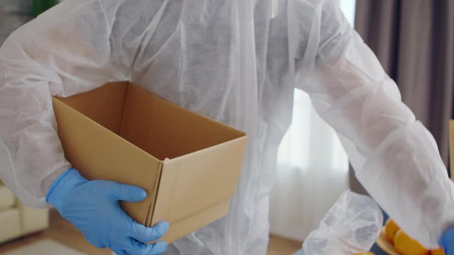 Close up of volunteer packing food in box for delivery wearing protective suit during gloabal covid-19 pandemic
