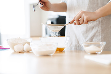 Cropped image of caucasian young woman preparing dough while cooking pie
