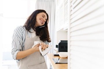 Image of laughing woman talking on cellphone while cooking pie