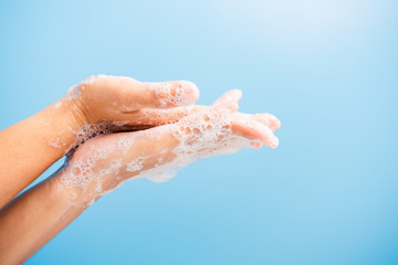 Fototapeta premium Closeup body care Asian young woman washing hands with soap have foam, hygiene prevention COVID-19 or coronavirus protection concept, isolated on blue background