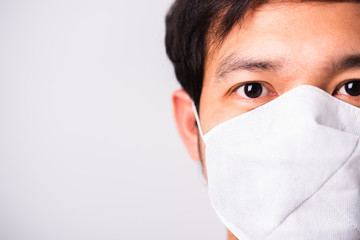 Closeup Asian handsome Man wearing surgical hygienic protective cloth face mask against coronavirus, studio shot isolated white background, COVID-19 medical concept