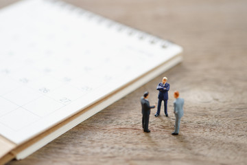 Miniature people businessmen standing on white calendar using as background business concept and finance concept with copy space  for your text or  design.