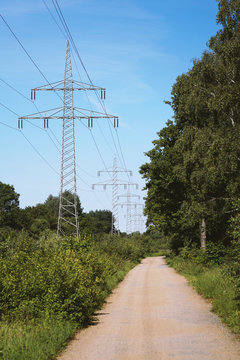 Transmission Line Or Overhead Power Cable With Electricity Pylons Along Rural Dirt Track Country Lane Path Through German Countryside