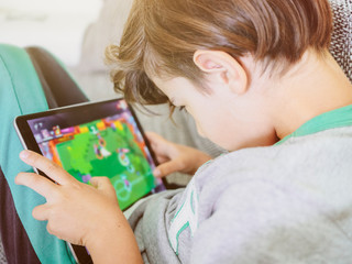 child with tablet in wrong posture playing addictive video game