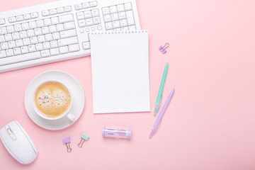 Woman office workplace with cup of coffee and pastel colorful stationery accessories on pink background. Top view