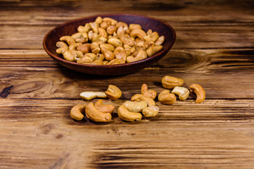 Ceramic plate with roasted cashew nuts on a wooden table