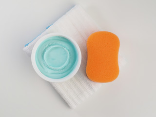 Dry dishwashing with orange sponge and white towel for wiping.