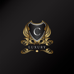 Shield logo in gold color with letter C Logo. Elegant logo vector template made of wide silver alphabet font on shield frame ornate style.