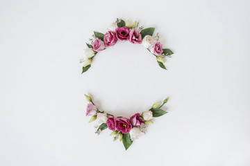 Round wreath frame made of roses flowers on white background. Flat lay, top view festive holiday celebration. Mockup with blank copy space for text