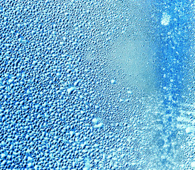 Drops of water on blue glass as an abstract background