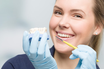 smiling female dentist is working on dental imprint with artificial dentition in detal laboratory