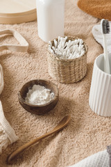 Beauty health care composition with ear sticks in rattan casket, towel, powder, toothbrushes on beige towel. Female beauty treatment routine concept
