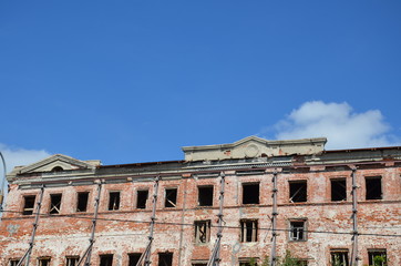 Obraz premium Brick facade of an abandoned old building with windows.