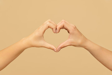 Love. Female Hands Making Heart Shape Against Beige Background. Caucasian Woman Folding Fingers And Palms As Romantic Symbol.