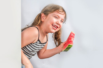 Happy little child with watermelon. Smiling kid girl eating watermelon slice, against white wall background, Copy space