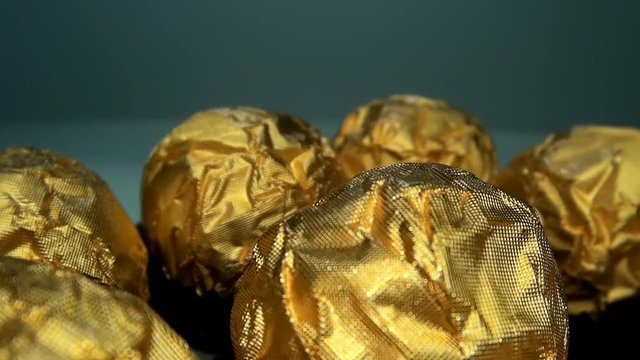 The camera moves slowly over a tasty and beautiful chocolate balls bonbon with golden wrapper . Macro. Closeup. Shallow depth of field. Ultra small special camera