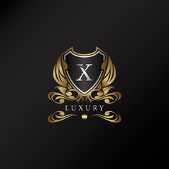 Shield logo in gold color with letter X Logo. Elegant logo vector template made of wide silver alphabet font on shield frame ornate style.
