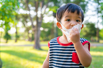 Little asian boy wearing protective pm 2.5 medicine mask outside, Child portrait.