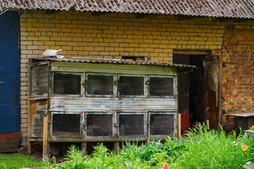 Fototapeta na wymiar Rural life. Old cages for rabbits near a barn in the outback of Latvia, May 2020.