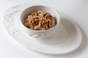 Spelled porridge with walnut. Proper nutrition concept. White background.