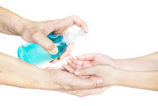 Closeup of father pushing alcohol sanitizer gel pump dispenser to son hand isolated over white background - people with alcohol sanitizer prevent bacterias and COVID-19 virus protection concept.