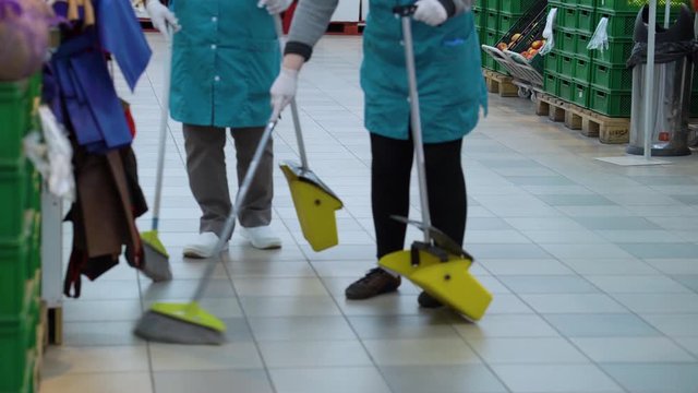 Cleaning service workers sweeping floor in supermarket